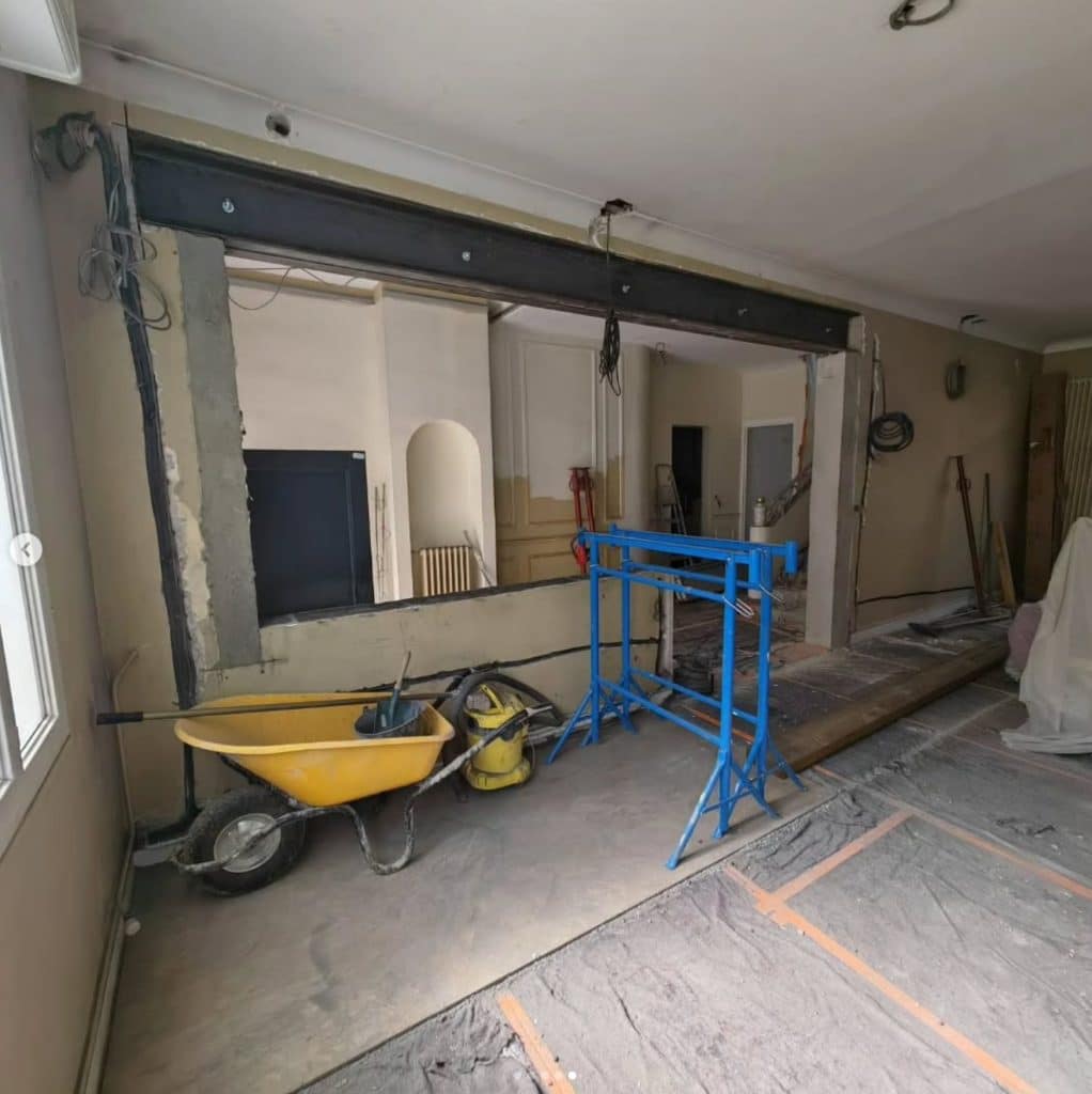 Chantier de rénovation montrant l'ouverture d'un mur porteur avec poutre métallique et étais de soutien
