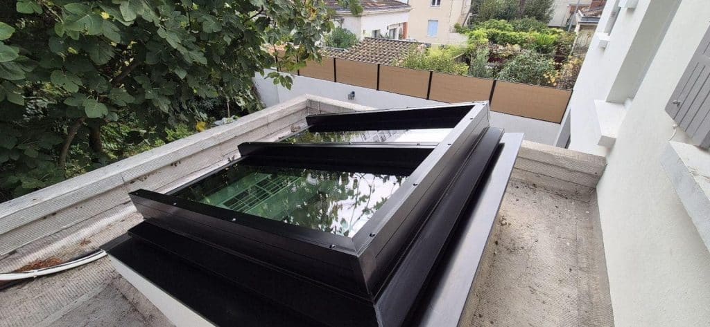Verrière de toit en aluminium noir installée sur toiture plate, apportant lumière naturelle à l'intérieur